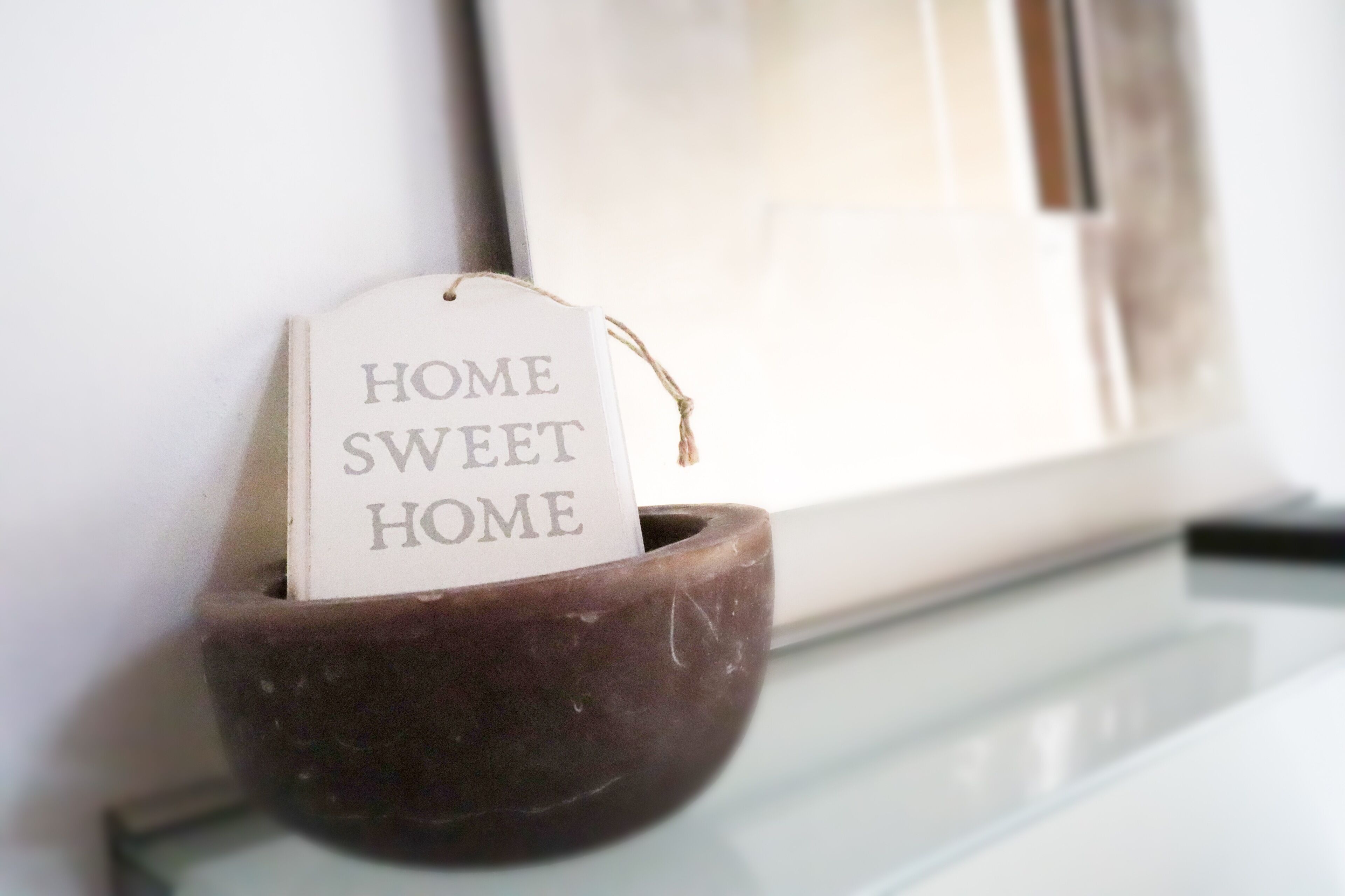 Eine dunkelbraune Keramikschale mit einem Schild, auf dem der Text 'HOME SWEET HOME' vor weißem Hintergrund steht.