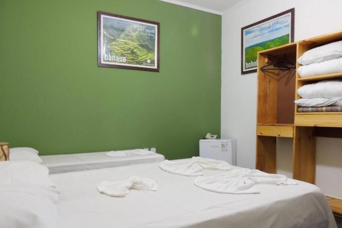 Una habitación de hotel con dos camas, una litera de madera y dos cuadros enmarcados en la pared.