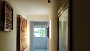 A narrow hallway with a tiled floor, a ceiling light fixture, and framed pictures on the walls. - Hotel Oriente (Itajuba)