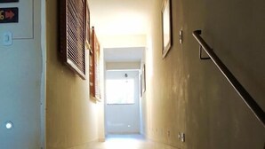 A staircase leading to a room with a window, a door, and a wall-mounted light fixture. - Hotel Oriente (Itajuba)