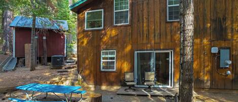 Une cabane en bois dotée d’un patio couvert, d’une petite terrasse et d’une grande fenêtre.