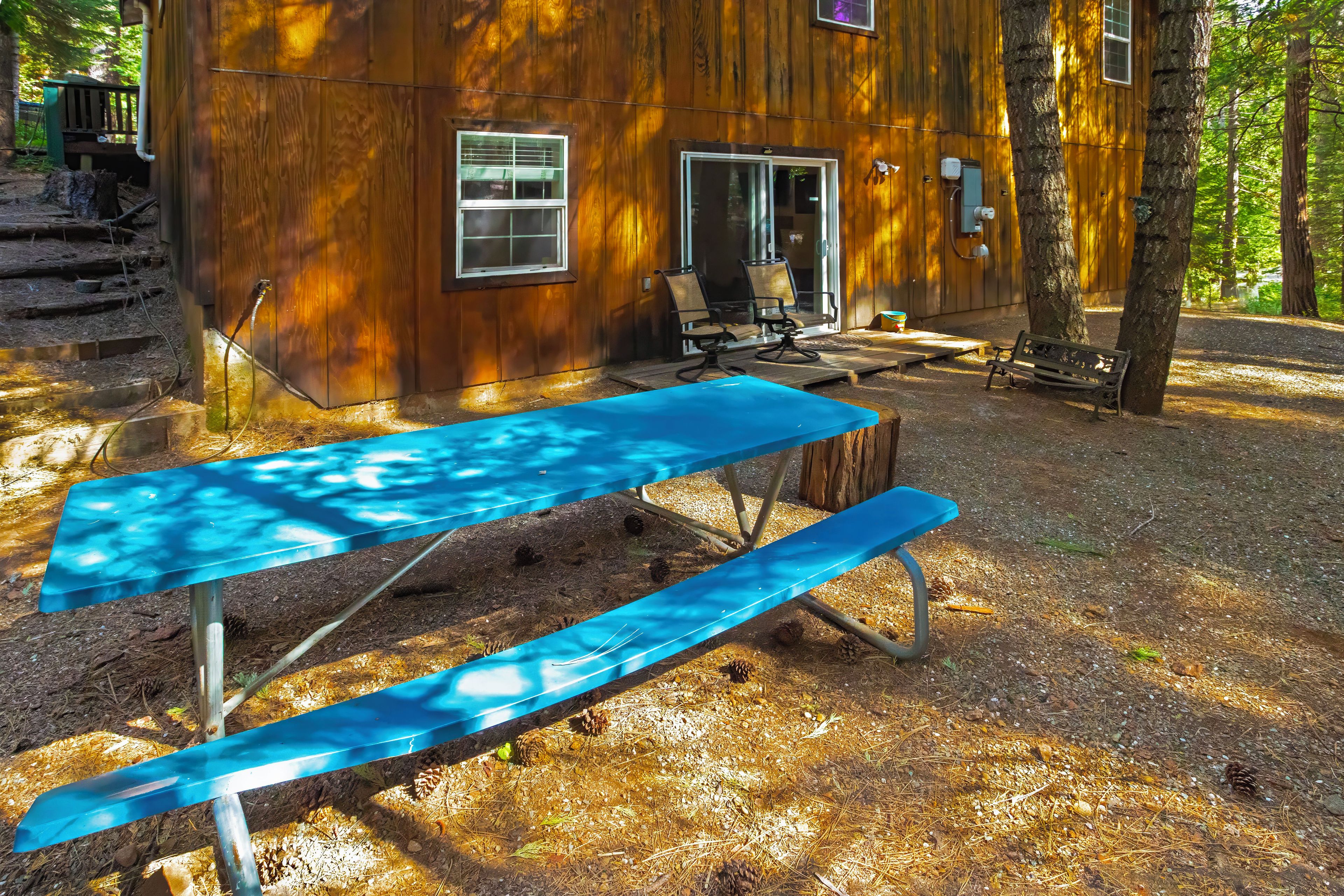 A rustic wooden cabin with a covered patio area, a table, and chairs.