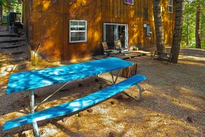 A rustic wooden cabin with a covered patio area, a table, and chairs.
