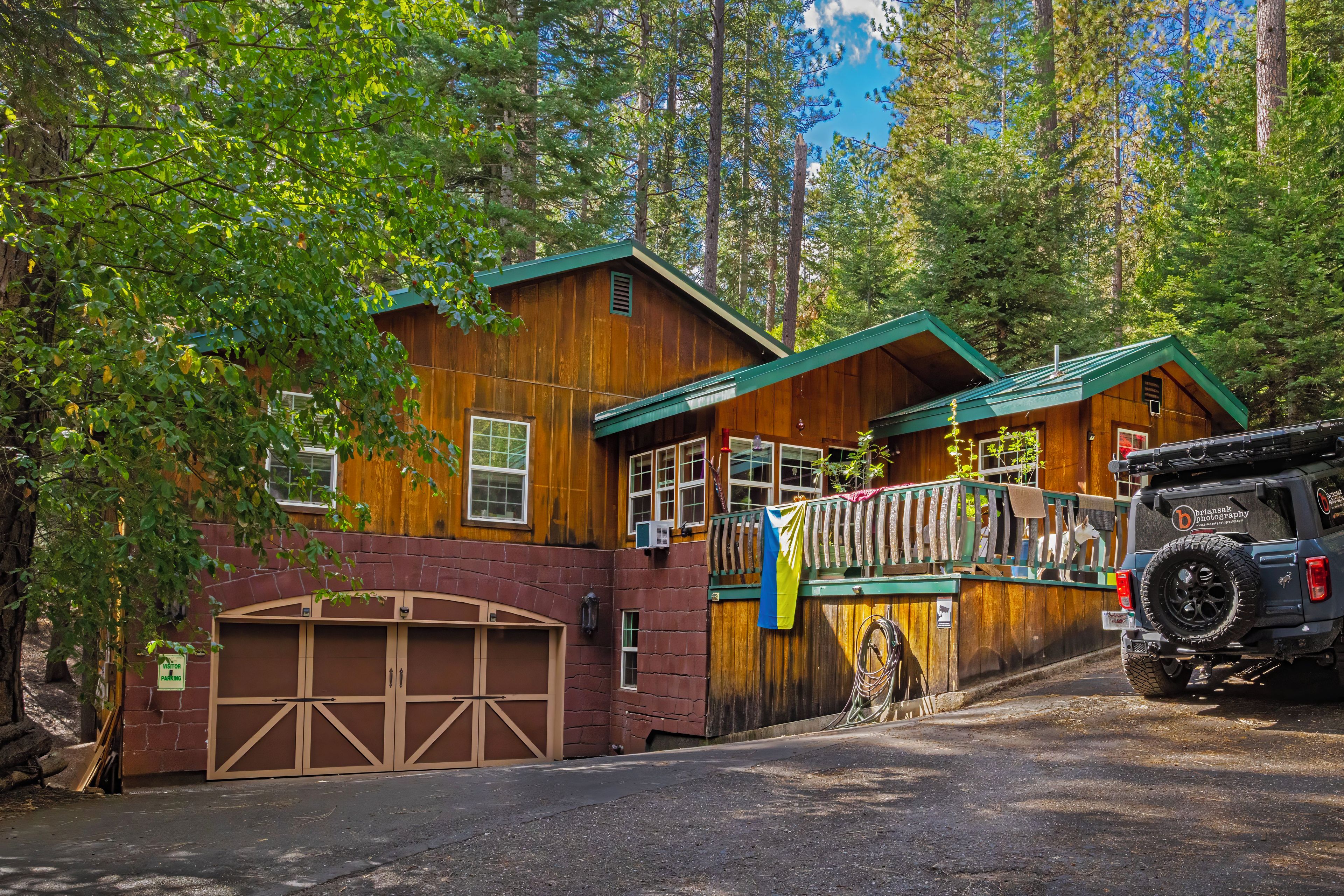 Une cabane avec un garage, une véranda et un véhicule garé devant.