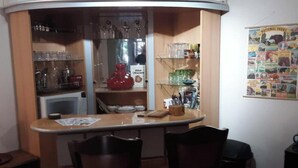 Une pièce d’angle comprenant une table à manger, des chaises, un réfrigérateur et une affiche accrochée au mur.