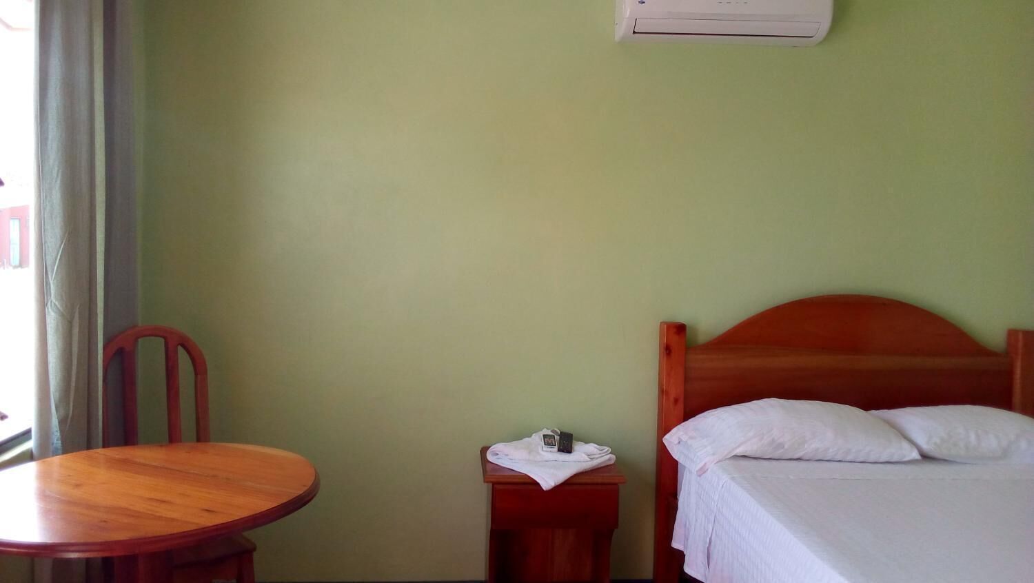 Una habitación con una cama, una mesa de madera y una silla.