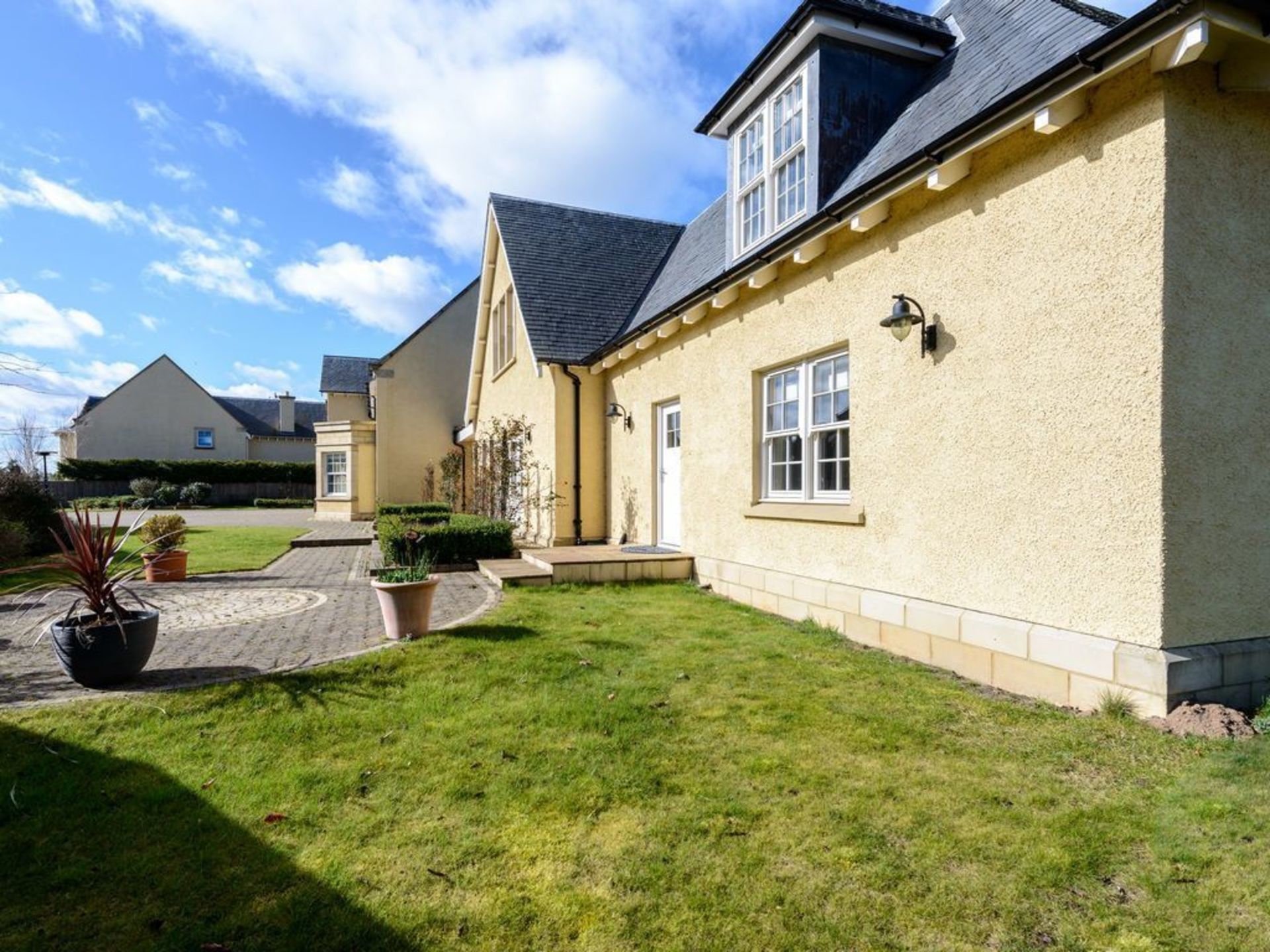 A two-story house with a well-maintained lawn and a driveway leading to the front door.
