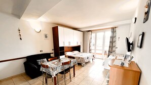 A room with a bed, a desk, a dining table, and a kitchenette. - Residence le Rose (Bibbona)