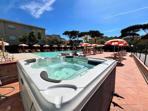 A pool area with hot tubs, lounge chairs, and umbrellas. - Residence le Rose (Bibbona)