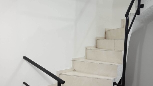 A staircase with a black handrail and white steps, leading to a landing. - Portal Del Pinar (Bogotá)