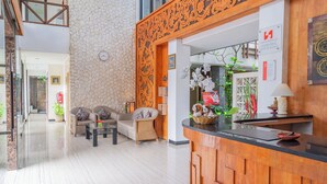 A modern hotel lobby with a stone wall, wooden reception desk, and comfortable seating area. - Swiss-Belinn Seminyak (Denpasar)