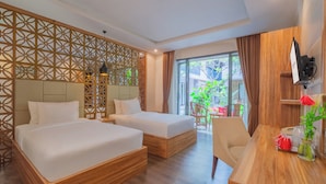 A hotel room with two beds, a wooden desk, a TV, and a view of the outdoors. - Swiss-Belinn Seminyak (Denpasar)