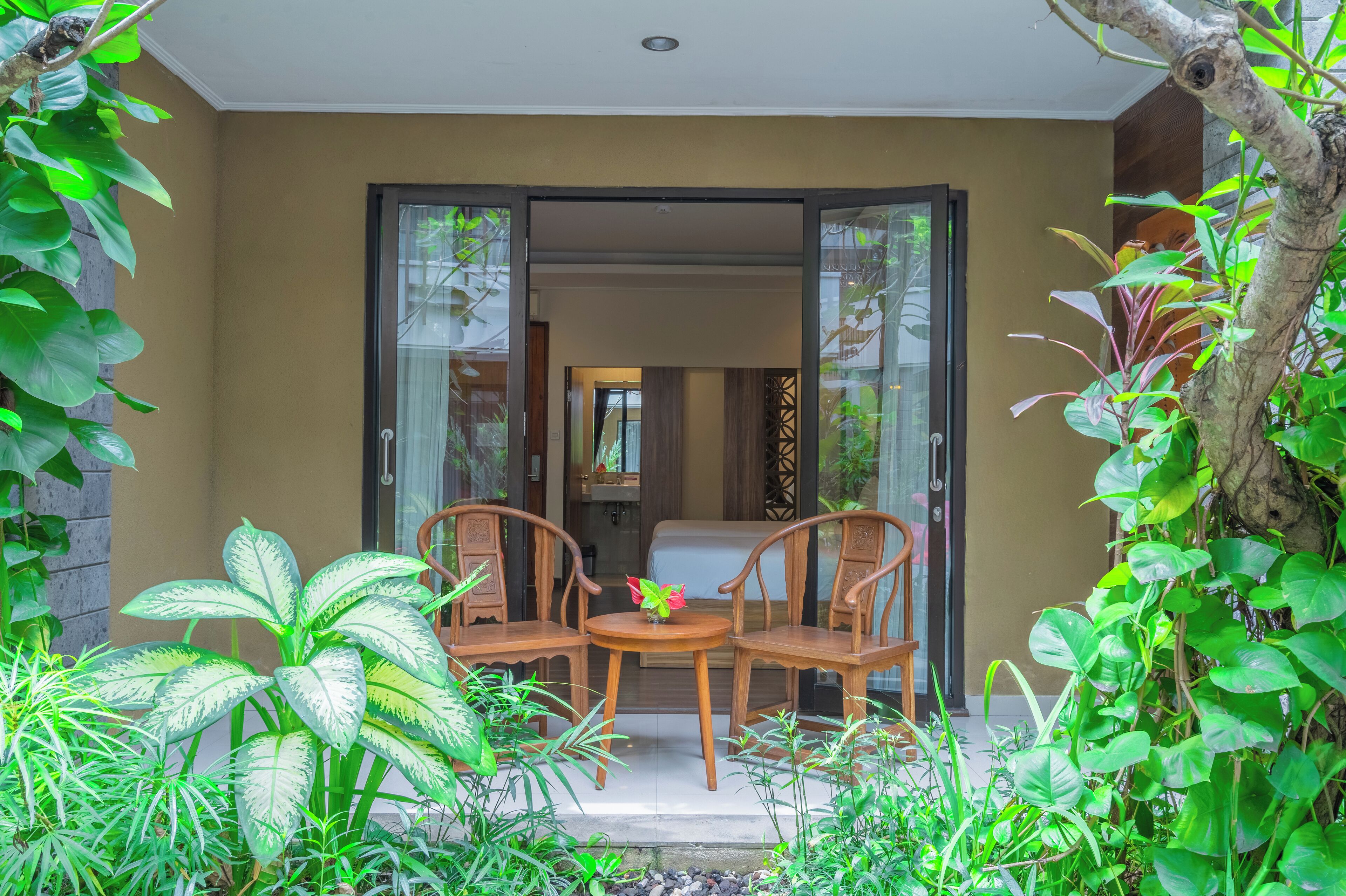 A room with a bed, a small table with chairs, and a view of the outside.