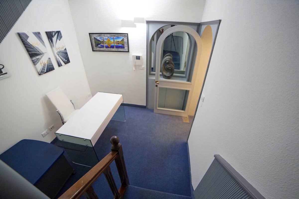 A stairwell with a blue carpet, a white desk, and a door with a glass panel.