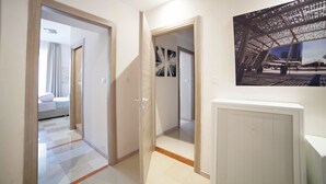 A hotel corridor with a bed in the background, a radiator, and a framed picture on the wall. - IMHOME - Cadorna House (Milan)
