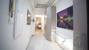 A modern hotel hallway with a glass display case, a framed artwork, and a bed in the background. - IMHOME - Cadorna House (Milan)