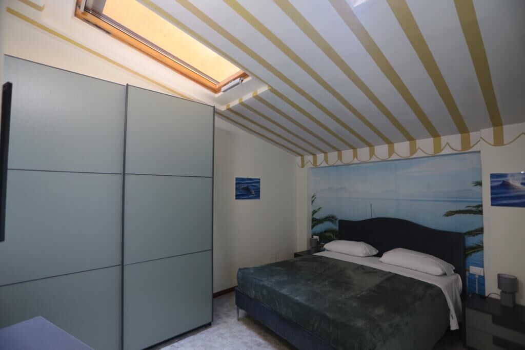 A bedroom with a bed, a wardrobe, a skylight, and a beach mural on the wall.