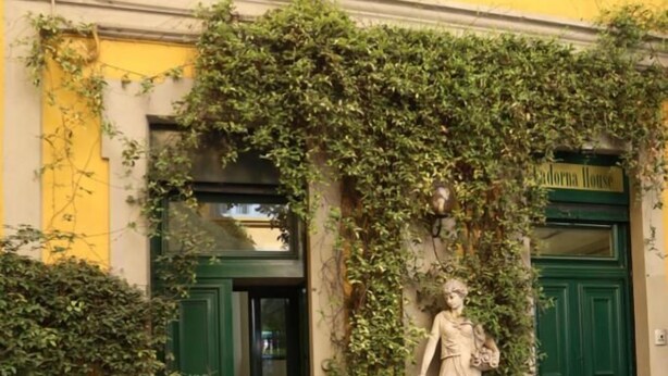 A building facade with green doors, a statue, and potted plants. - IMHOME - Cadorna House (Milan)