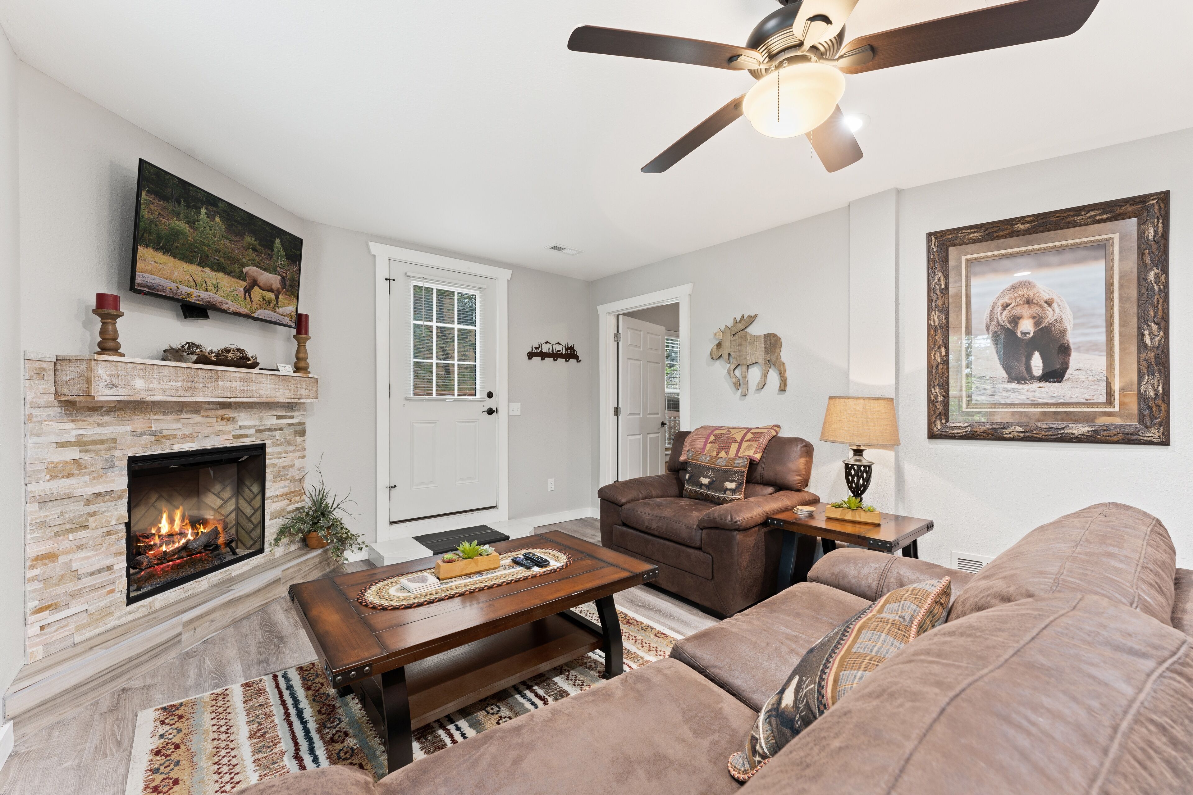 A living room with a fireplace, a sofa, a coffee table, and a television mounted on the wall.