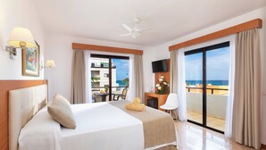 A hotel room with a large bed, a desk with a chair, a TV, and a balcony with a view of the ocean. - Hotel Don Manolito (Puerto de la Cruz)
