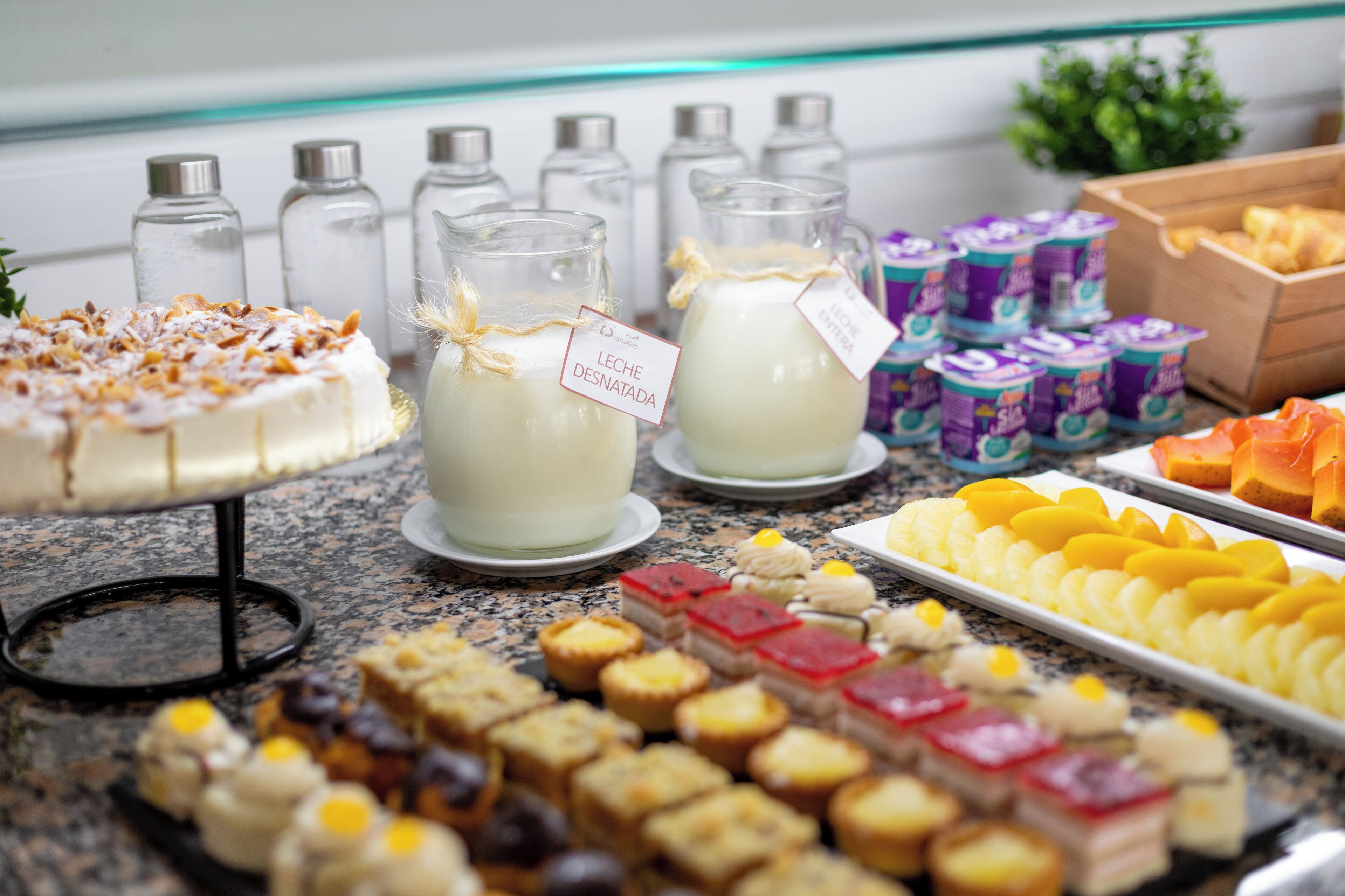 A buffet table with various food items, including a cake, milk, and assorted pastries.
