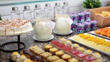 A buffet table with various food items, including a cake, milk, and assorted pastries.
