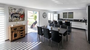 A modern kitchen with a dining area, large windows, and a clock on the wall.