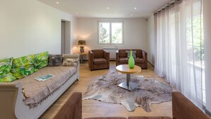 A modern living room with a sofa, two armchairs, a coffee table, and a rug.