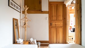 Un dormitorio con dos camas, un armario de madera y un tendedero de madera.