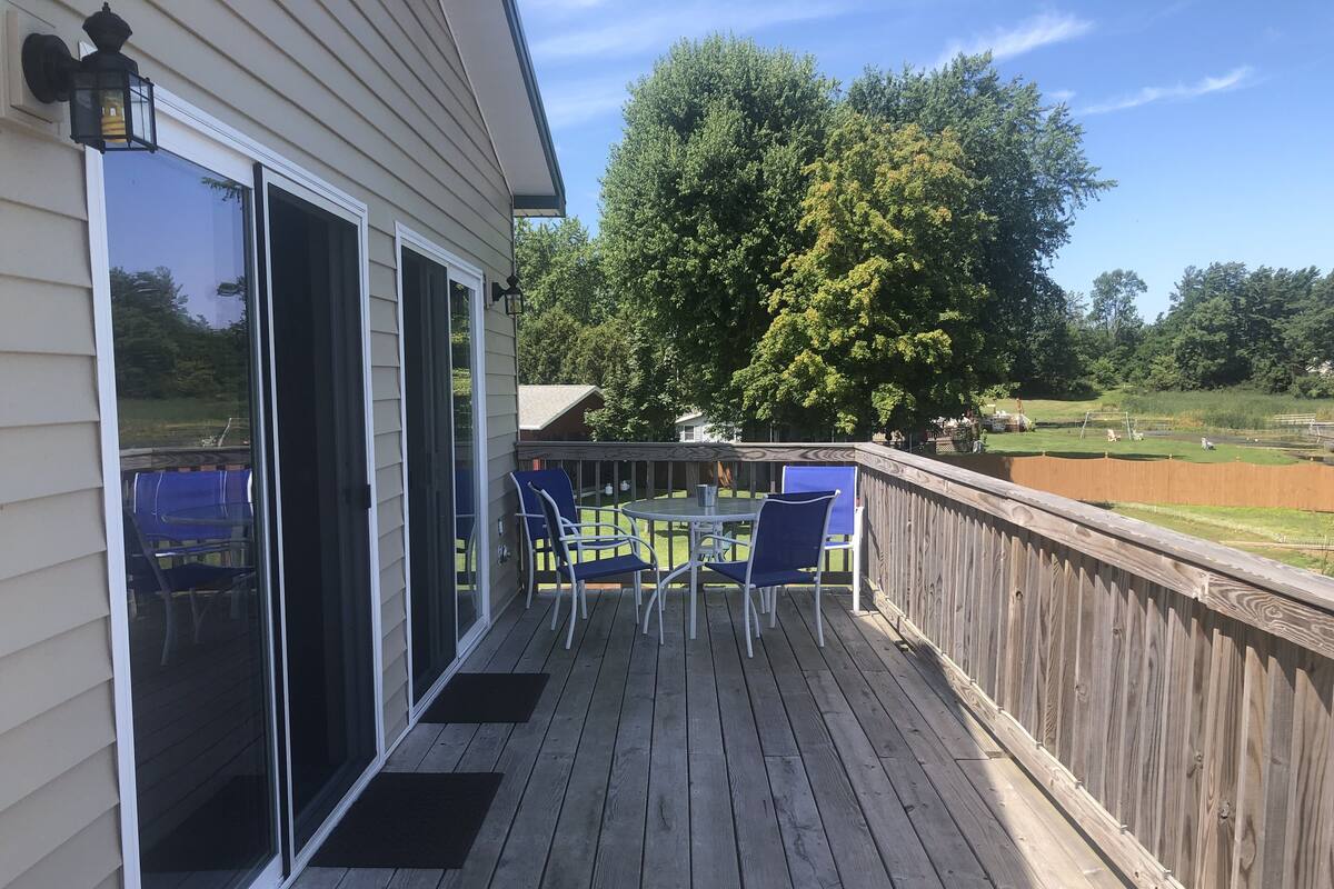 A wooden deck with a glass door leading to a patio area.