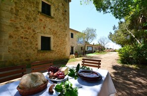 Un rústico edificio de piedra con una mesa dispuesta para una comida, mostrando pan, uvas y un plato.