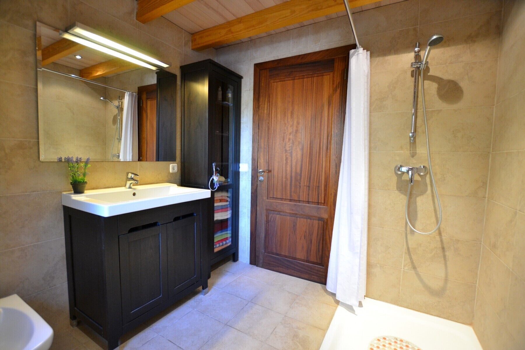 A bathroom with a sink, mirror, shower, and toilet.