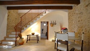 A staircase leading to an upper floor, a dining area with chairs and a table, and a wall with a textured stone pattern. - Son Palanca, Finca 5starshome Mallorca (Sineu)