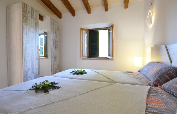 Un dormitorio con cama, ventana, lámpara y vistas al exterior.