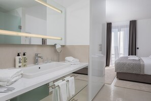 Un baño de hotel moderno con un espejo grande, lavamanos dobles y cabina de ducha de vidrio.
