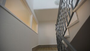 A staircase with a metal railing, a window on the left, and a plain wall.