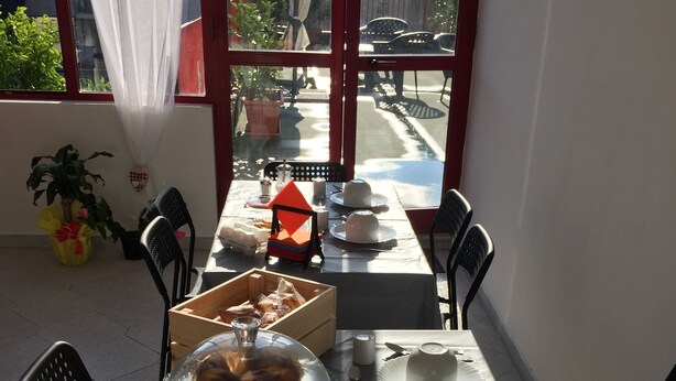 A dining area with a table set for a meal, chairs, and a view through a window.