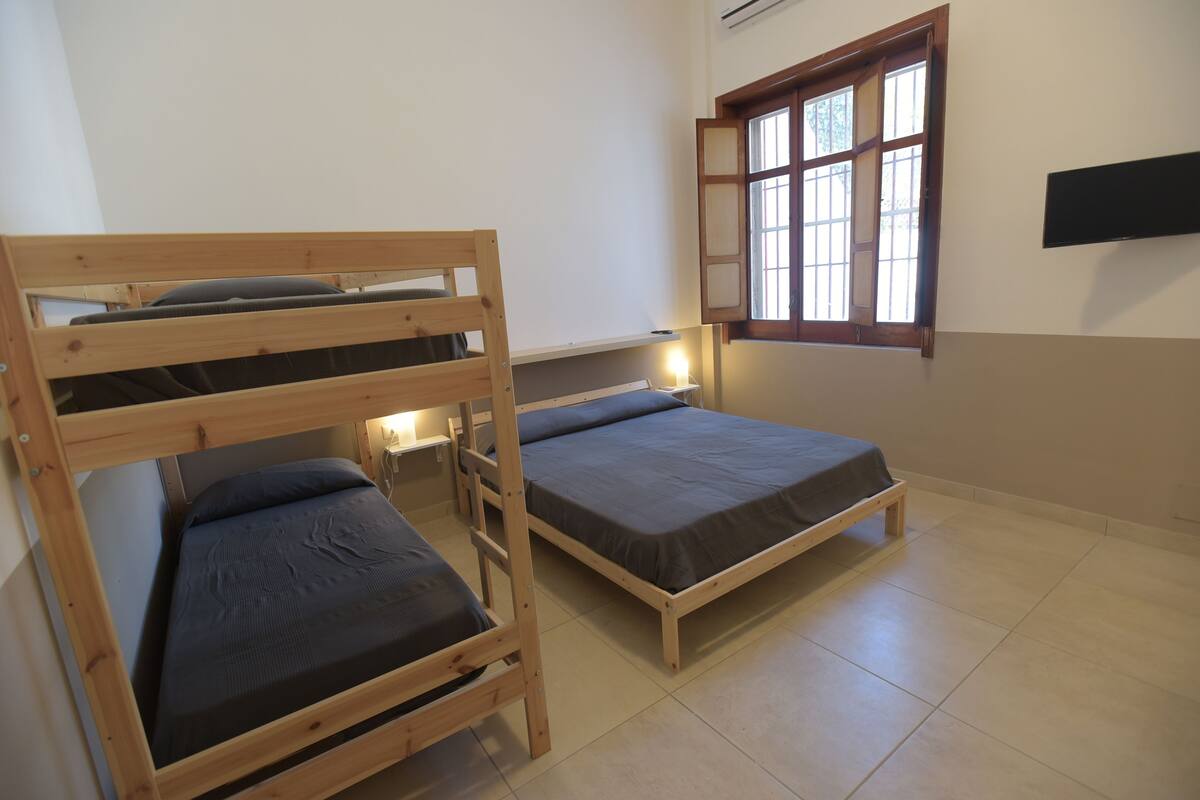 Un dormitorio con dos literas, una ventana de madera y un televisor instalado en la pared.
