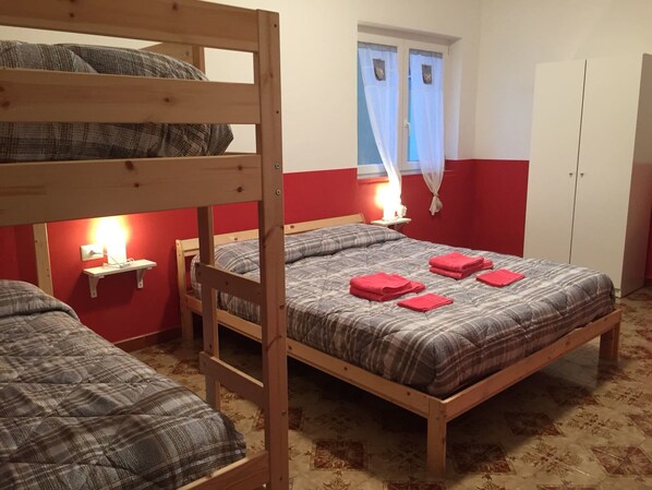 A dormitory room with two bunk beds, a single bed, a bedside table with a lamp, and a window with curtains. - Sunset B&B Pompei (Pompei)