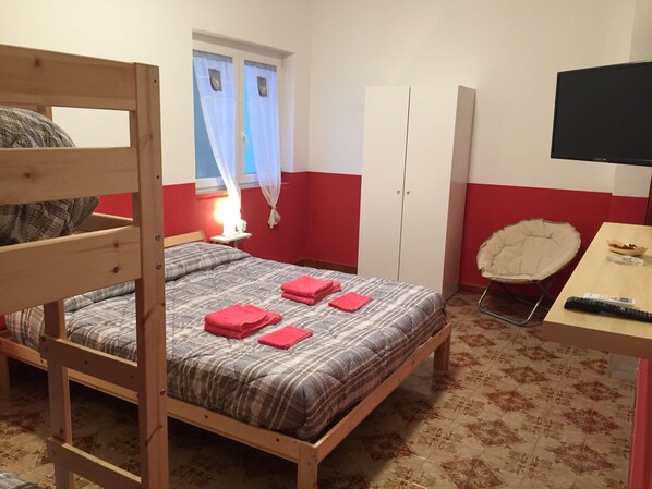Un dormitorio con una cama litera, un escritorio con silla, un armario y un televisor.