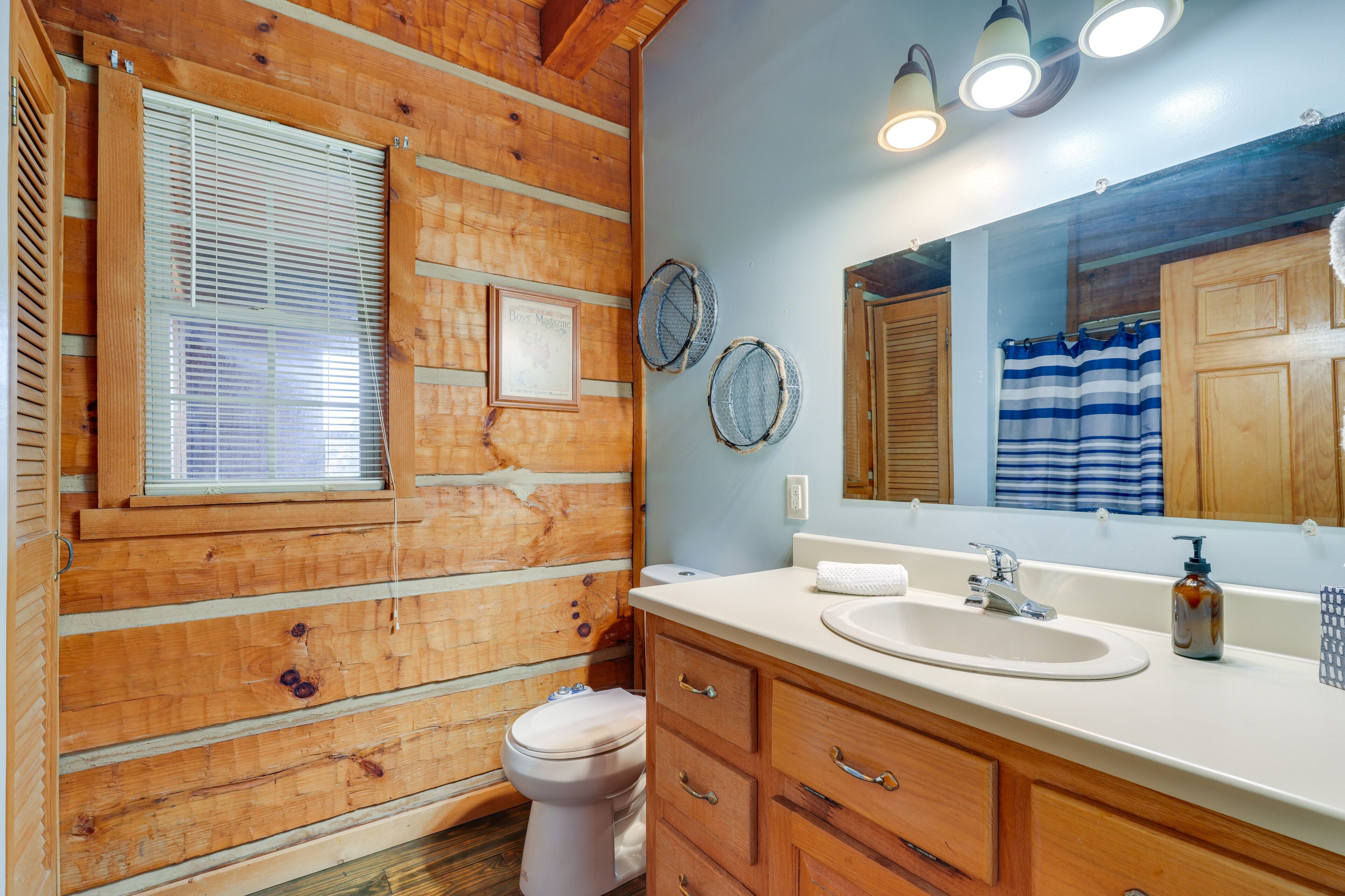 Een badkamer in chaletstijl met toilet, wastafel, badkamermeubel en een grote spiegel.