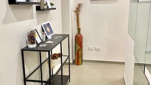A modern interior with a black metal console table, a vase, and a framed picture on the wall. - Ambasciatori B&B (Catania)