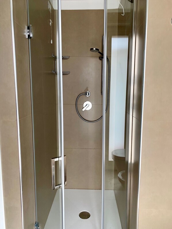 A glass-enclosed shower stall with a control panel, a handheld showerhead, and a handheld massage nozzle. - Ambasciatori B&B (Catania)