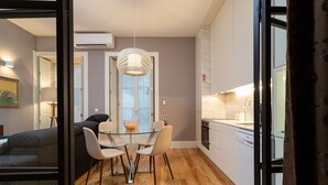 Ett modernt kök med en matplats, med ett glasbord, stolar och en hängande lampa.