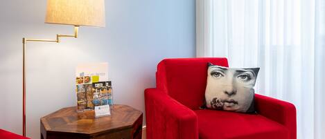 A modern living room with a red armchair, a round wooden side table, and a floor lamp.