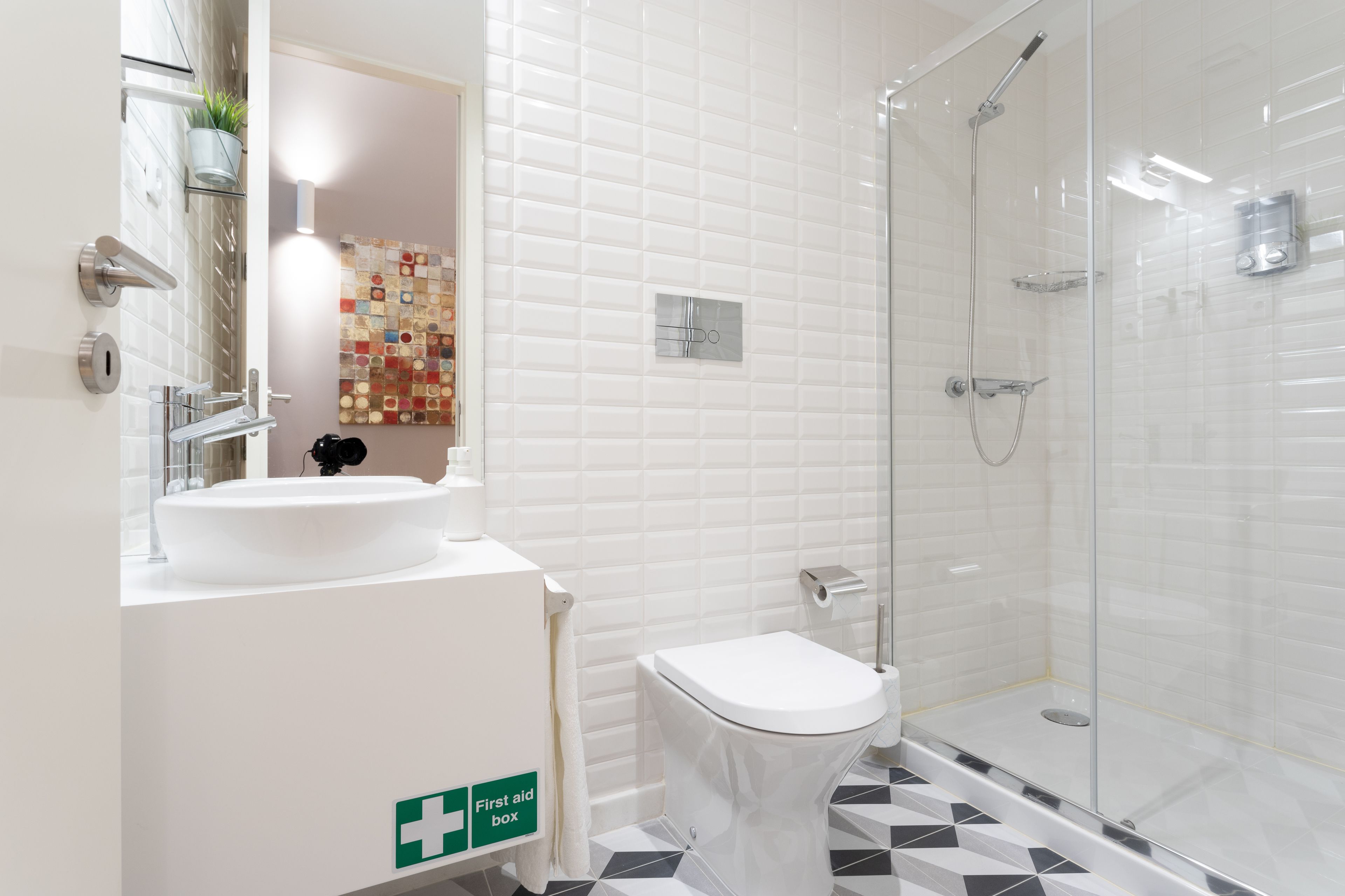 A modern bathroom with a white sink, toilet, and glass shower enclosure.
