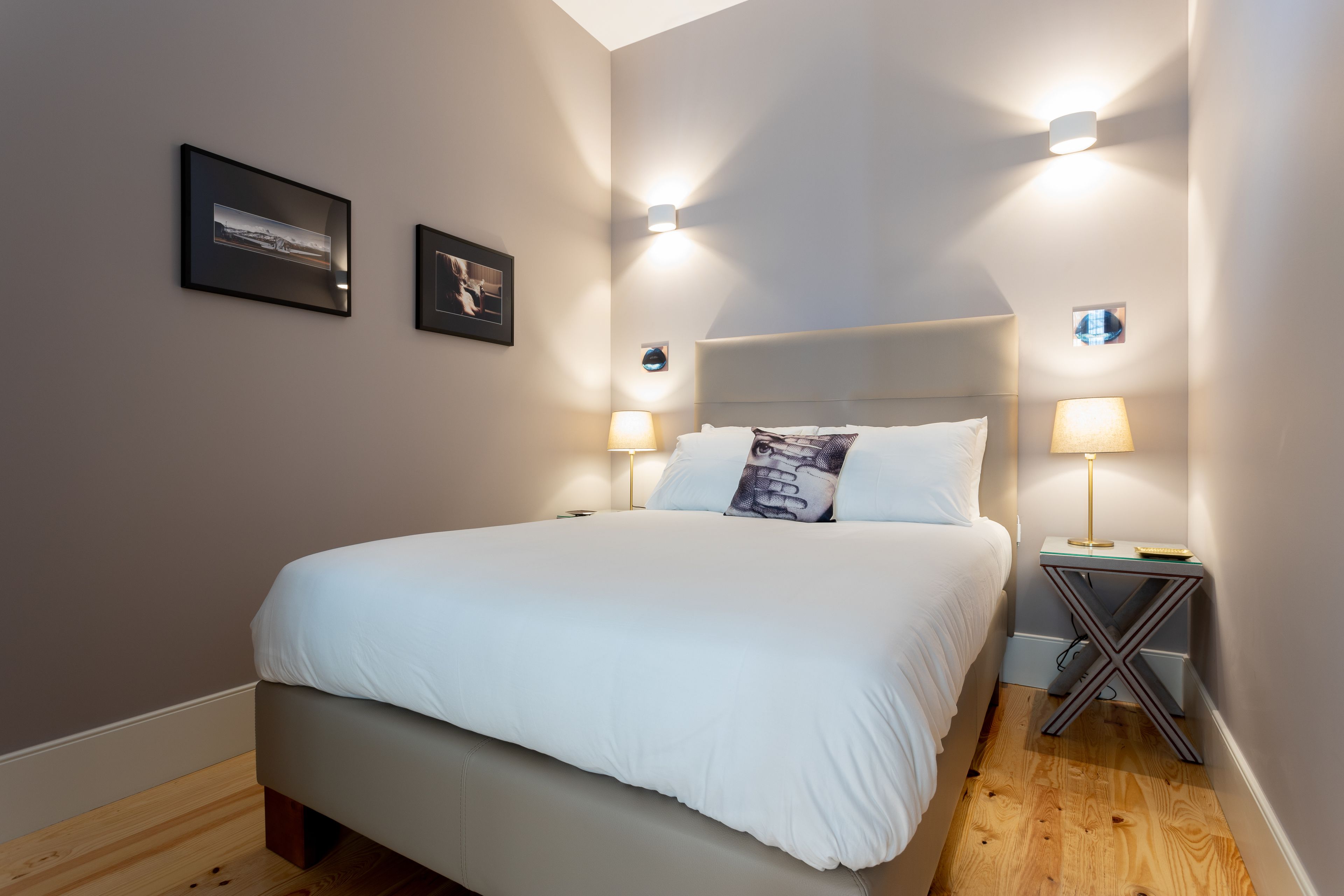 Un letto rifatto con lenzuola bianche, due quadri appesi alle pareti e due lampade ai comodini.