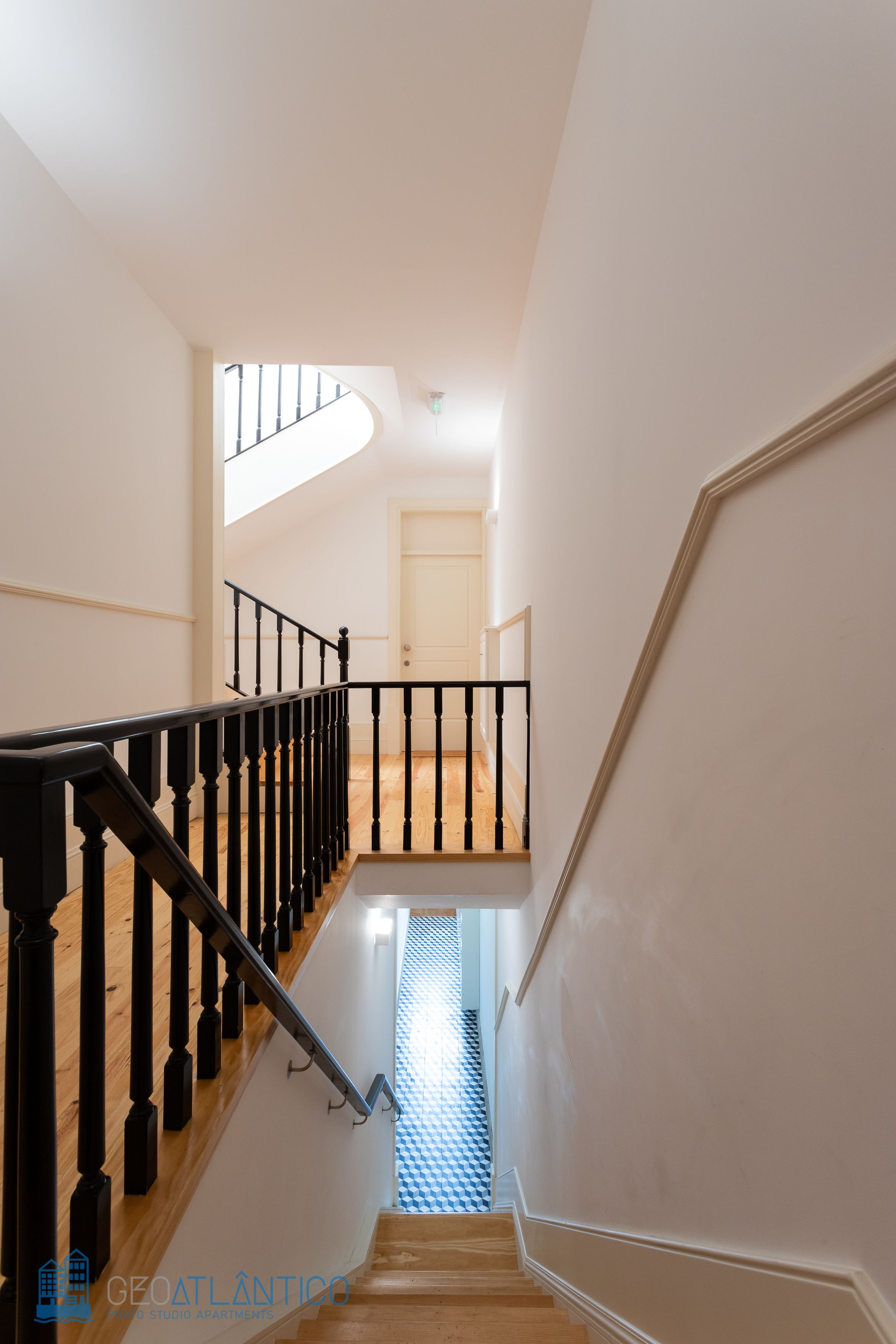A staircase with black railings and wooden steps leading to a landing.