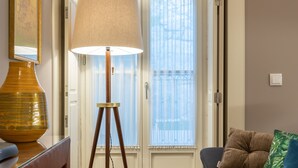 Ett rum med en soffa i mörk färg, en golvlampa och ett litet bord i trä.
