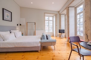 Een hotelkamer met een bed, een slaapbank, een televisie en een eethoek.